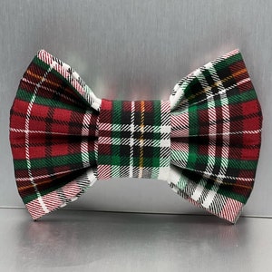 May include: A red, green, white, and black plaid bow tie. The bow tie is made of fabric and has a classic bow shape.
