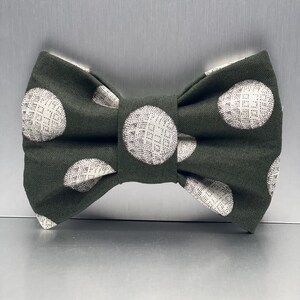 May include: A green bow tie with white polka dots. The polka dots have a textured pattern.