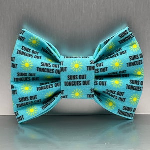 May include: A turquoise blue bow tie with a repeating pattern of yellow suns and the text "Suns Out Tongues Out".
