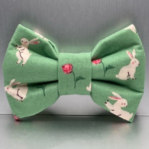 May include: A green bow tie with a white bunny rabbit and pink flower pattern.