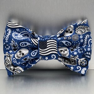 Peut inclure: Noeud papillon bleu avec un motif paisley représentant des crânes, des flammes et des motos. Le noeud papillon comporte également un petit drapeau américain au centre.