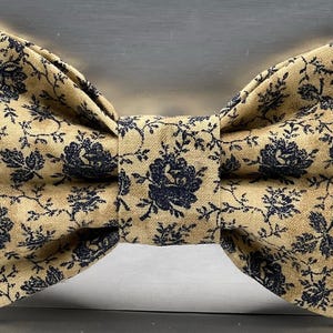 May include: A white ceramic mug with a black handle and the text "But First, Coffee" in a bold, black font. The mug is set against a blurred background, suggesting a cosy setting.