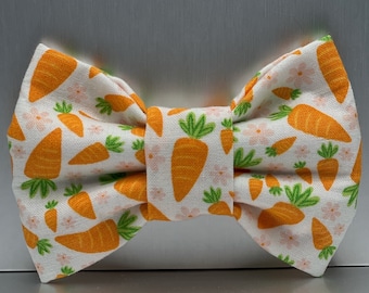 May include: A white bow tie with a pattern of orange carrots and small pink flowers.