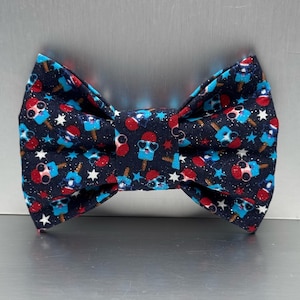 Peut inclure: Un nœud papillon bleu marine avec un motif répété de glaces rouges, bleues et blanches portant des lunettes de soleil et des étoiles blanches. Le nœud papillon est de forme classique, parfait pour ajouter une touche amusante à n'importe quelle tenue.