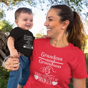 May include: A red and black matching set of t-shirts for a grandma and grandson. The shirts feature the text "Grandma and Grandson" with a fist bump graphic and the text "A bond that can't be broken".