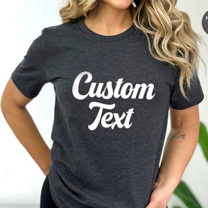 May include: A heather dark grey t-shirt with the text "Custom Text" in white, stylized in a retro font.