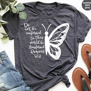 May include: Heather dark grey t-shirt with a white butterfly graphic and the text "Do not be conformed to this world be transformed Romans 12:2".