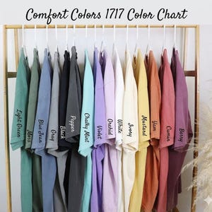A rack displaying a variety of colorful t-shirts, each with a different color and a corresponding name written on it.