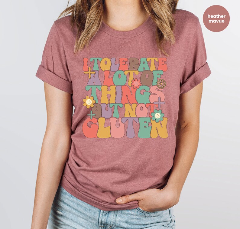 May include: A heather mauve t-shirt with a retro-style graphic that reads "I tolerate a lot of things but not gluten".