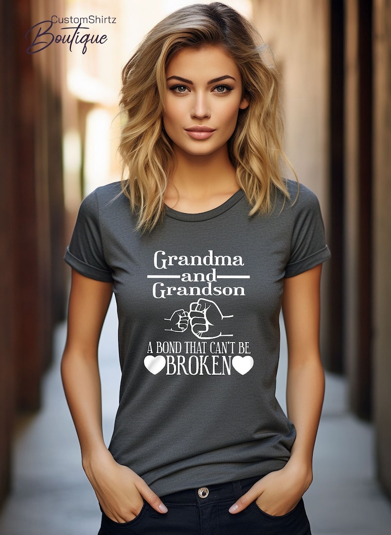 May include: A gray t-shirt with a white graphic that says "Grandma and Grandson" with a fist bump design and the text "A bond that can't be broken" with two hearts.
