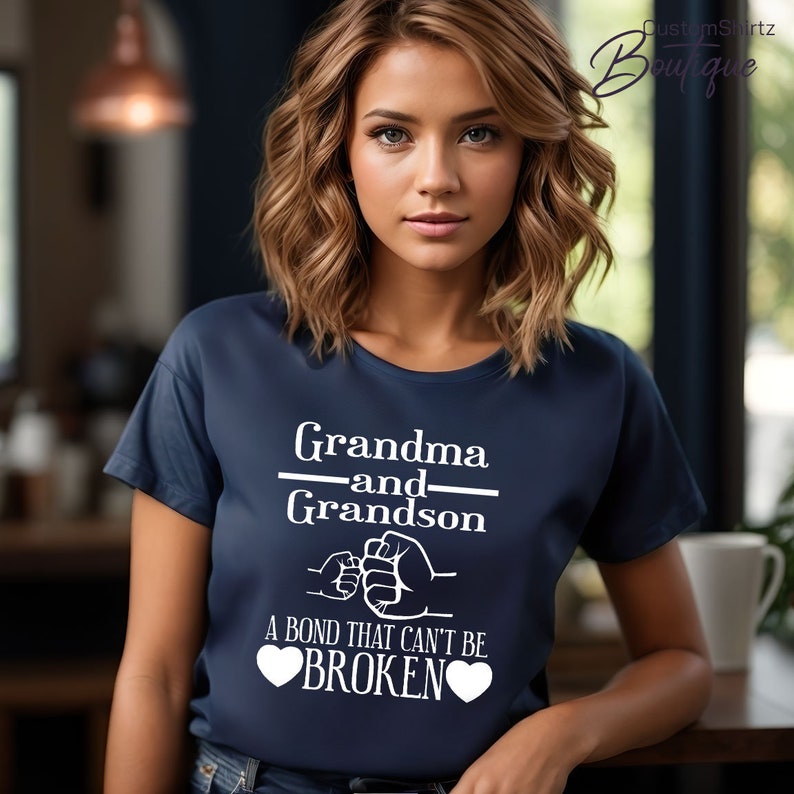 May include: A navy blue t-shirt with white text that reads "Grandma and Grandson" with a fist bump graphic and the text "A bond that can't be broken" with two white hearts.