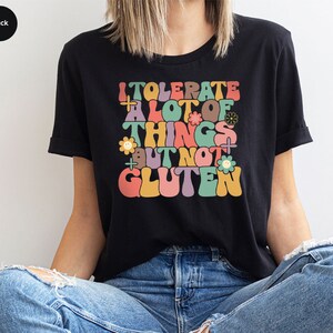 May include: A black t-shirt with a colorful graphic that says "I tolerate a lot of things but not gluten".