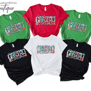 K&ouml;nnte beinhalten: F&uuml;nf T-Shirts in verschiedenen Farben mit dem Text "Gastro Crew" in bunten Buchstaben. Die Shirts sind gr&uuml;n, rot, wei&szlig;, schwarz und dunkelgrau.