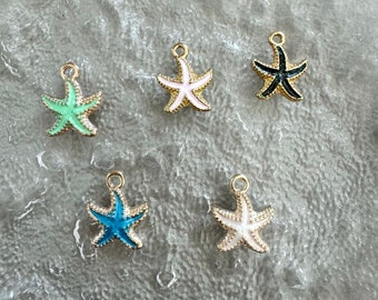 Pode incluir: Cinco pingentes de estrela do mar dourados com tinta de esmalte em diferentes cores: verde, rosa, preto, azul e branco.