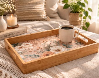 Può includere: Un vassoio da portata rettangolare in bambù con un motivo floreale sulla base, caratterizzato da fiori bianchi e color pesca e foglie verdi. Una tazza in ceramica bianca riempita di caffè nero poggia sul vassoio dotato di manici laterali.