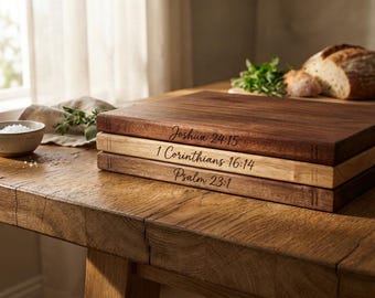Può includere: Una pila di tre taglieri rettangolari in legno con testo inciso. Il tagliere superiore è in legno scuro con Joshua 24:15, quello centrale in legno chiaro con 1 Corinthians 16:14 e quello inferiore in legno scuro con Psalm 23:1 sui bordi.