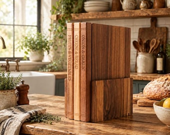 Può includere: Un set di tre taglieri in legno disposti verticalmente in un supporto abbinato. I taglieri presentano scritte incise FRUITS & VEGETABLES, CHEESE & BREAD e ONION & GARLIC, con venature del legno naturali visibili sulla superficie.