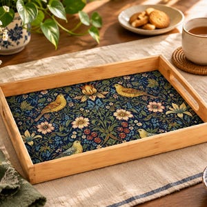 May include: A rectangular wooden serving tray with cutout handles, featuring a dark blue interior base decorated with a repeating pattern of yellow birds, light-colored flowers, and green foliage. The tray has a natural light wood finish.