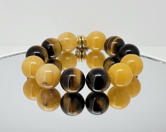 May include: A bracelet made with yellow and brown tiger's eye beads and golden yellow beads. The bracelet has a gold clasp.