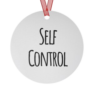 May include: A round, silver-colored ornament with the words "SELF CONTROL" in black, handwritten-style font. A red ribbon is attached at the top for hanging. The ornament is a simple, yet impactful, decorative item.