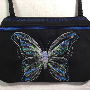 May include: A black fabric purse with a zipper closure and a blue butterfly embroidered on the front.