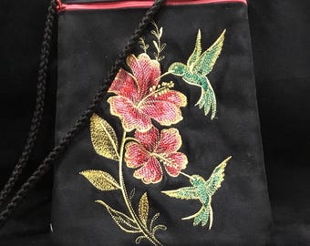 NUOVO FORMATO VERTICALE! Borsa Glimmering Hummingbirds ricamata da 9 1/2" x 6 1/2" su finta pelle scamosciata nera. Borsa con cerniera foderata e tracolla.