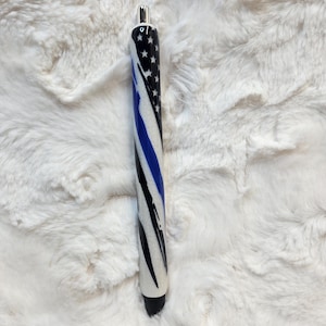 May include: A black and white pen with a blue and white American flag design and a thin blue line.