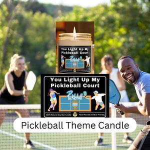 Peut inclure: Une bougie en cire de soja sur le thème du pickleball. La bougie est dans un pot en verre transparent avec une étiquette noire qui indique "You Light Up My Pickleball Court". L'étiquette présente également un court de pickleball et une balle de pickleball. La bougie est coulée à la main et écologique.