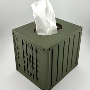 Könnte beinhalten: Eine grüne Tissuebox in Form eines Versandcontainers. Die Box hat ein weißes Taschentuch, das oben herausragt.
