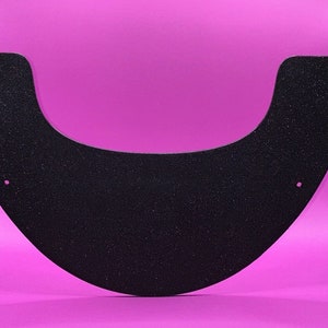 Puede incluir: Tapa de asiento de inodoro de plástico negro con superficie texturizada. La tapa está diseñada para adaptarse a un asiento de inodoro estándar.