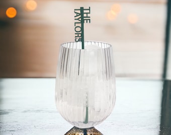May include: A clear glass with ice and a green stir stick with the text "THE TAYLORS" on it.