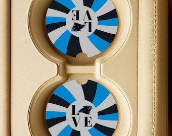 Op de afbeelding: Twee ronde auto-onderzetters met een radiaal ontwerp in zwart, lichtblauw en grijs. Het woord "LOVE" is verticaal gedrukt, met een panterlogo. De onderzetters zijn geplaatst in een beige bekerhouder in de auto.