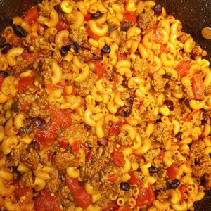 K&ouml;nnte beinhalten: Nahaufnahme eines Topfes gef&uuml;llt mit einer Mischung aus Makkaroni, Hackfleisch, schwarzen Bohnen, Mais und gew&uuml;rfelten Tomaten. Die Nudeln sind gekocht und die Zutaten sind in einer dicken Sauce vermischt.