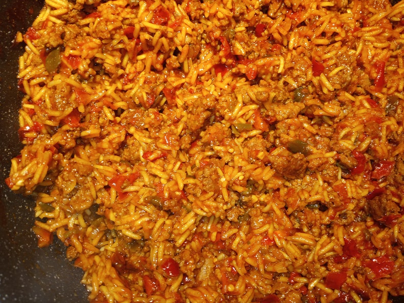 K&ouml;nnte beinhalten: Nahaufnahme einer Bratpfanne gef&uuml;llt mit einer Mischung aus gebratenem Hackfleisch, Reis und roten Paprikaschoten. Die Mischung ist mit einer roten Sauce gew&uuml;rzt und sieht nach einem herzhaften und schmackhaften Gericht aus.