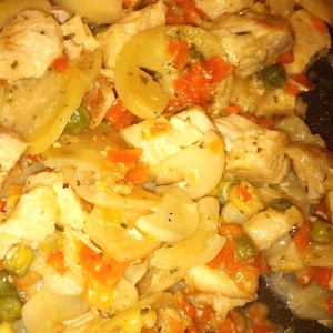 May include: A close-up of a skillet filled with a chicken and potato dish. The dish is made with diced chicken, potatoes, carrots, and peas. The chicken and potatoes are cooked in a creamy sauce.