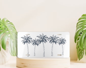 May include: White metal license plate with a design of five palm trees in a row, drawn in a dark blue color.