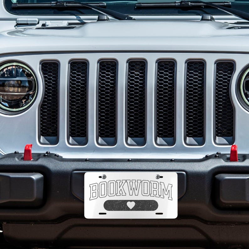 May include: A white Jeep Wrangler with a black grille and a number plate that reads "BOOKWORM" with a heart symbol.