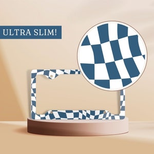 May include: A blue and white checkered license plate frame with the text "ULTRA SLIM!" printed on it. The frame is made of metal and has a sleek, modern design.