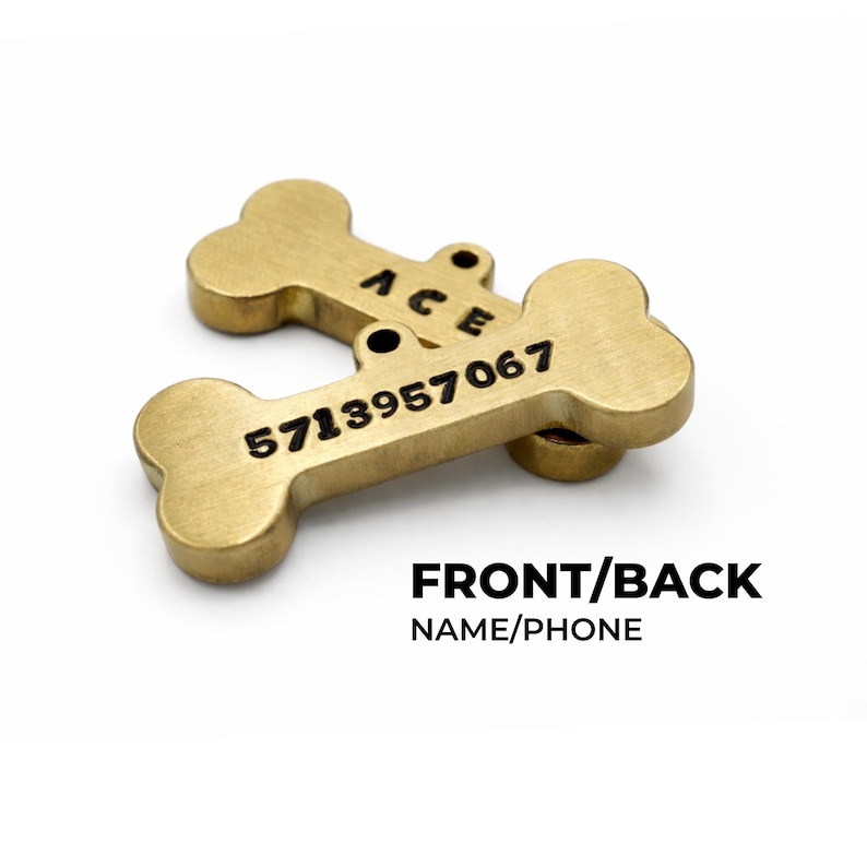 Two gold-colored, bone-shaped pet tags. One tag is stacked on top of the other. The top tag has the name "ACE" engraved on it. The bottom tag has the phone number "5713957067" engraved on it. The text "FRONT/BACK NAME/PHONE" is below the tags. Custom dog ID tag engraved with pet name and phone number, personalized dog tags for pets