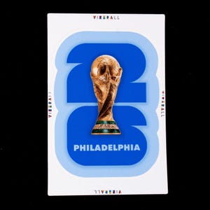 May include: A rectangular sticker featuring the large blue numbers 26 with a gold FIFA World Cup trophy centered over the digits. The word PHILADELPHIA is printed in white below the trophy. The text VIZRALL appears on the edges of the sticker.