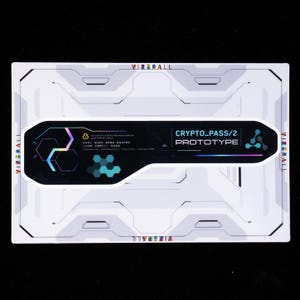 May include: A rectangular white card featuring a futuristic mechanical design and the text VIZERALL. Centered is a black, elongated, key-shaped sticker labeled CRYPTO_PASS/2 PROTOTYPE, decorated with geometric hexagon patterns and colorful accents.