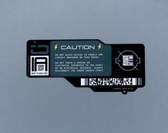 May include: A rectangular black and dark gray caution label featuring yellow lightning bolt icons, white text reading CAUTION, and instructions regarding electrical panels. It includes a QR code, a barcode, and a charge indicator label.