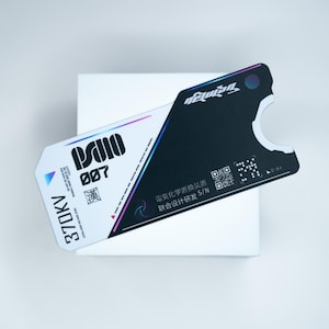 Può includere: Una carta in stile futuristico con un design bianco e nero. La carta presenta il testo "PSIIO 007" e "370KV" in grassetto. Il lato nero ha un codice QR e testo giapponese. La carta ha una forma unica con un ritaglio.