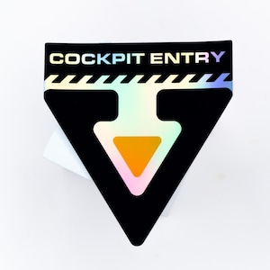 May include: A triangular black sticker featuring the text COCKPIT ENTRY in holographic lettering. Below the text is a white diagonal striped border and a large downward-pointing arrow with a solid orange center and a holographic outline.