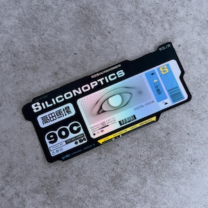May include: A black rectangular sticker with the text "SILICONOPTICS" and "DIGITAL VISION". The sticker features a stylized eye graphic with a gradient color scheme. Additional text includes "高田馬場" and "90C".