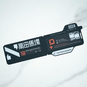 May include: A black and white rectangular label with text in multiple languages. The label includes the words "SUPER-CAPACITOR" and "Avoid contact with water." There are also several warning symbols and a QR code.