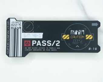 Può includere: Un adesivo rettangolare nero con grafica e testo tecnici in bianco e giallo. Presenta le parole SUPER-CAPACITOR, PASS/2 e CAUTION, insieme a un codice a barre, il numero di serie S/N 48-1 e l'avvertenza DO NOT BLOCK ACCESS TO PANELS AND CIRCUIT BREAKERS OR FUSE BOXES.