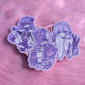 May include: Three stickers featuring anime-style illustrations in shades of purple. One shows a figure with a skeleton torso and butterfly accents. Another has floral elements covering the face. The third depicts a figure with lavender sprigs.