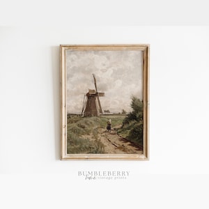 Op de afbeelding: Een vintage schilderij van een windmolen in een landelijk landschap. De windmolen is bruin en wit, met een houten constructie en een wit zeil. Het landschap is groen en bruin, met een zandweg die naar de windmolen leidt. Een klein figuurtje loopt op de weg.