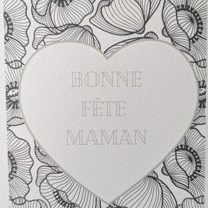 Può includere: Biglietto d'auguri con un design a forma di cuore e le parole "BONNE FÊTE MAMAN" al centro. La carta presenta un motivo floreale di papaveri in bianco e nero, creando un'estetica delicata e artistica.